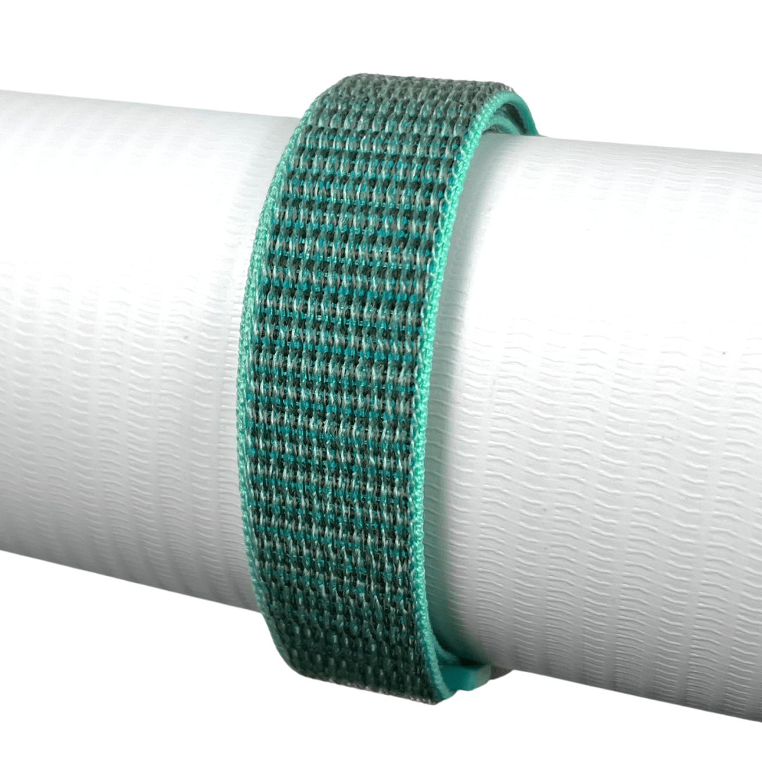 Zelený textilní řemínek s jemnou strukturou, upevněný na bílém válcovém podstavci.